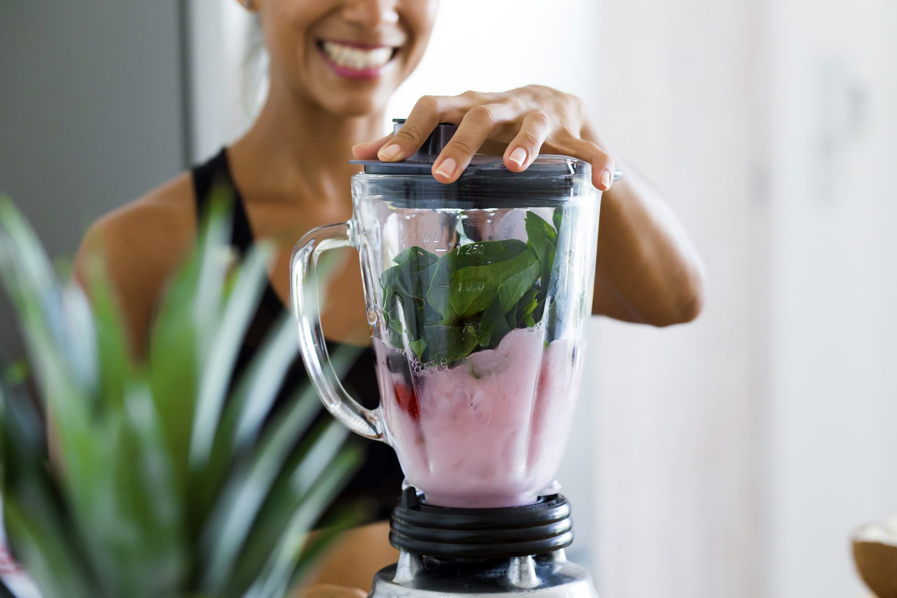 Woman,Blending,Spinach,,Berries,,Bananas,And,Almond,Milk,To,Make 6 easy ways to eat more vegetables
